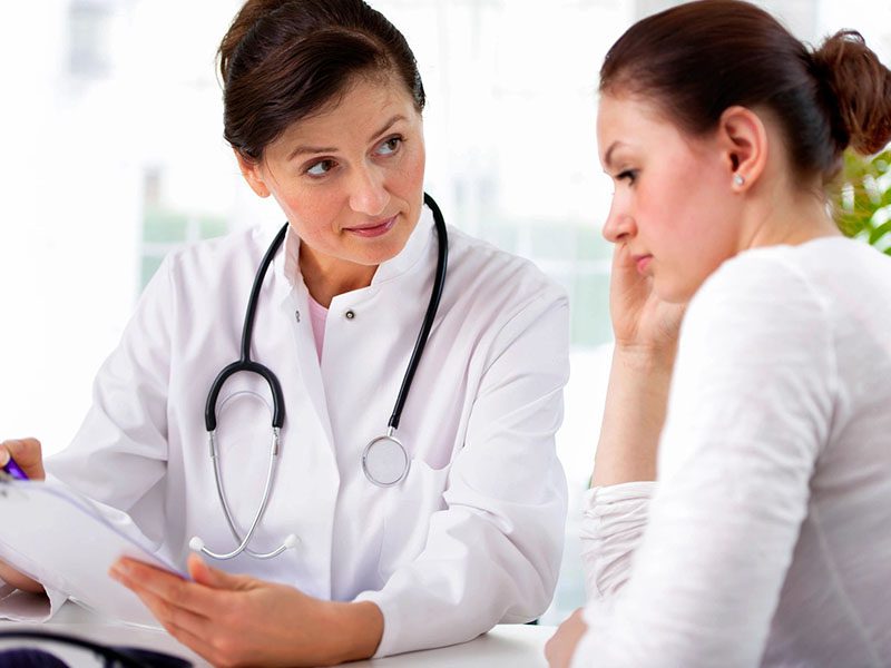 Female Doctor and Female Patient Looking Over Clipboard