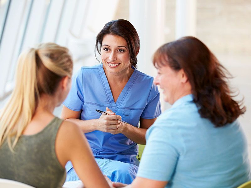 A group of women sitting around talking to each other.